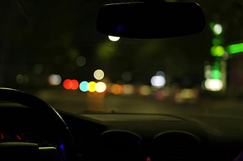 bokeh lights, blurred city lights, car interior, night driving, urban driving, city ambiance, night scene, car dashboard, rearview mirror, street lights, bokeh effect