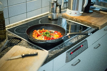 electric stove, modern kitchen, frying pan, colorful pan, eggs and vegetables, cooking, green vegetables, orange vegetables, black frying pan, kitchen setting, food preparation
