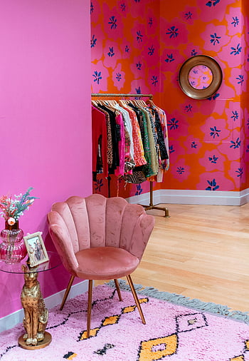 rosa Sessel, farbenfrohes Zimmer, Kleiderständer, schicke Boutique, lebendiges Dekor, Blumentapete, stilvolles Interieur, Boutique Atmosphäre, moderne Möbel, rosa Teppich, goldene Statue