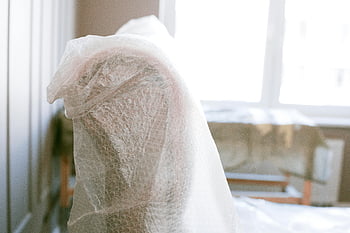 bubble wrap, furniture protection, moving, bright sunlit room, shallow focus, wrapped furniture, indoor scene, protective packaging, home moving, bubble wrap furniture, sunlit interior