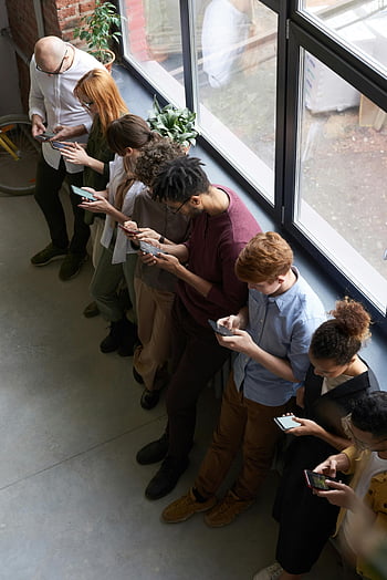 lidé drží telefony, rozmanití kancelářští pracovníci, smartphony, moderní pracoviště, připojení, skupina podle okna, pomocí chytrých telefonů, Kancelářské prostředí, Technologie na pracovišti, využití smartphonu, rozmanitý tým