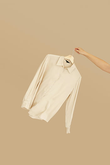 chemise de robe beige, réglage minimaliste, Hangle de maintien à la main, Polo blanc à manches longues, chemise simple, fond beige, mode minimaliste, tenue décontractée, chemise à manches longues, style minimaliste, affichage