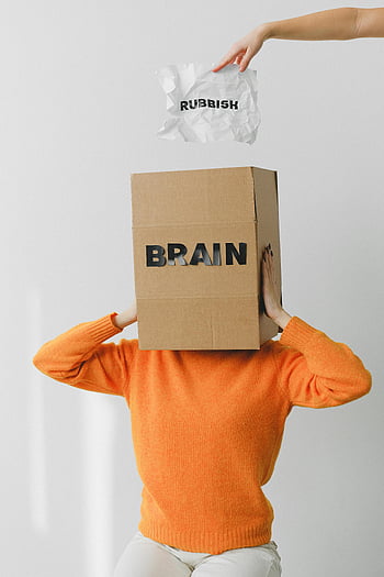 brain box, mental clutter, unrecognizable woman, orange sweater, discarding rubbish, symbolic image, mental health, brain label, paper rubbish, head covering, conceptual art