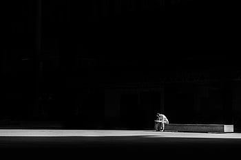 man sitting, concrete bench, black and white, solitude, contemplation, lone man, striking photo, urban scene, dark background, minimalistic composition, street photography