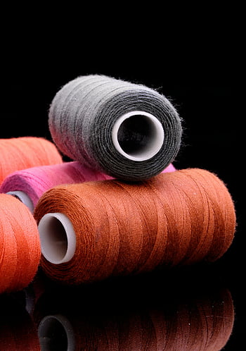 sewing threads, vibrant threads, stacked threads, glossy surface, dark backdrop, close-up threads, colorful threads, spools of thread, sewing supplies, textile materials, thread rolls