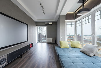 spacious living room, modern TV, projector, large screen, comfortable seating, modern living room, large windows, hardwood floor, contemporary design, home theater, cozy seating