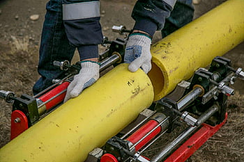 žluté trubky, pracovník, venkovní instalace, ruce, nástroje, detailní pohled, zařízení, instalace potrubí, konstrukce, venkovní práce, rukavice