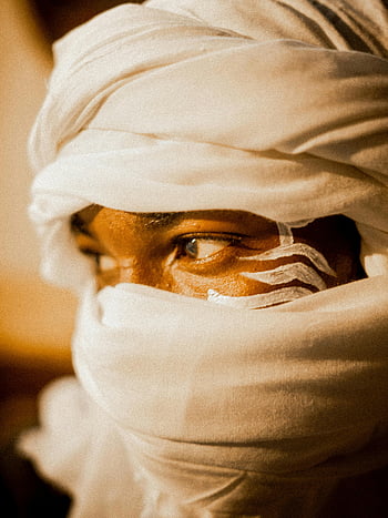 man in turban, white turban, painted face designs, close-up portrait, man's face, turbaned man, facial painting, traditional headwear, cultural attire, sepia tone, expressive eyes