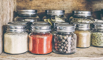 spices, glass jars, rustic wooden shelf, culinary use, assorted spices, clear glass jars, spice collection, kitchen storage, seasoning jars, spice organization, spice display