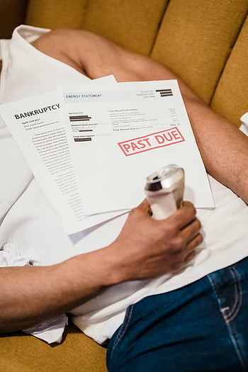 man lying down, unpaid bills, past due, holding can, drink can, sofa, financial stress, energy statement, bankruptcy notice, relaxed posture, financial trouble