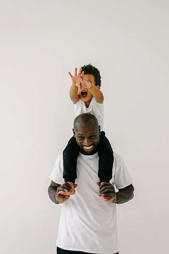 father and son, carrying child, family bond, joyful moment, indoor photo, shoulder carry, black family, white background, happy family, fatherhood, child on shoulders