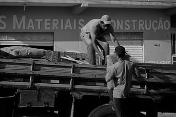 men loading bags, truck, construction materials, outside store, two men, loading, construction, materials, truck loading, construction store, men working