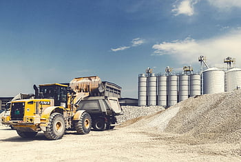 yellow heavy equipment, gravel yard, silos, sunny day, yellow loader, truck, industrial site, construction machinery, outdoor work, gravel pile, industrial landscape