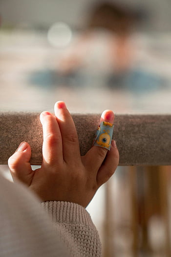 baby hand, colorful bandage, close-up photo, child's hand, poolside ledge, finger bandage, playful bandage, child injury, outdoor setting, small hand, poolside scene