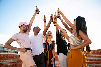 cheerful friends, multiethnic group, clinking beer bottles, event on terrace, diverse friends, enjoying drinks, laughter, sunny rooftop, rooftop party, group celebration, outdoor gathering