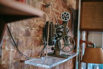 vintage film projector, rustic brick wall, cozy home interior, classic projector, shelf display, home decor, antique projector, interior design, vintage decor, film equipment, rustic interior