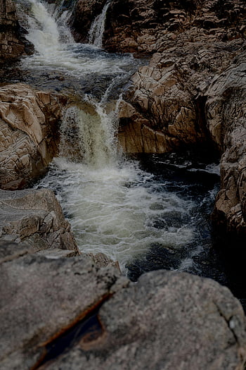 waterfall, cascading water, brown rocky river, jagged rocks, serene landscape, nature's beauty, rugged landscape, natural scenery, outdoor photography, river flow, rocky terrain