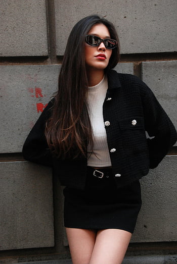 Yara D Leon, stylowa kobieta, długie włosy, okulary słoneczne, mur miejski, moda, strój, czarna kurtka, biały top, mini spódniczka, styl miejski