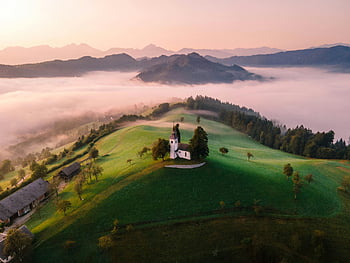 St Thomas Church, Northern Slovenia, lush green hills, misty mountains, aerial view, majestic landscape, rural scenery, church on hill, Slovenian countryside, serene nature, foggy valley