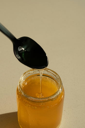 honey, spoon, jar, golden honey, dripping honey, black spoon, close-up, bright lighting, honey jar, honey pouring, honey spoon
