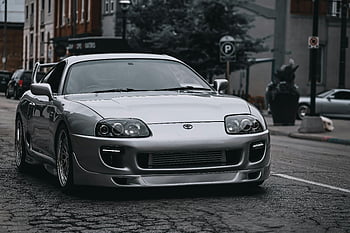 stříbrná Toyota Supra, městské ulice, Moderní automobilový design, elegantní auto, zaparkované auto, drsná ulice, toyota supra, stříbrné auto, městském prostředí, auto design, parkování na ulici