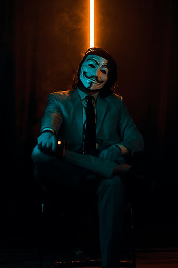 남자 정장을 입고있다., 익명의 가면, 어두운 공간, 수수께끼 같은 아우라, 앉은 남자, 슈트와 마스크, 어두운 배경, 신비한 인물, vendetta 마스크 용 V, 공식적인 옷차림, 대기 조명