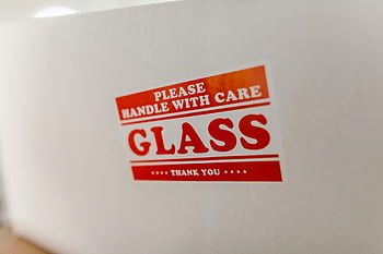 fragile package, close-up shot, glass packaging, handle with care, warning text, white box, glass label, fragile label, shipping label, package warning, fragile warning