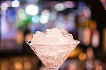 martini glass, crushed ice, cocktail glass, colorful bokeh, nightclub setting, elegant drink, shallow depth, bar scene, evening ambiance, cocktail presentation, bokeh lights