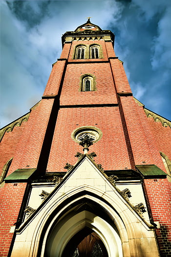 chiesa storica, mattone rosso, torre della chiesa, Inquadratura dal basso, cielo blu luminoso, architettura gotica, edificio religioso, dettagli architettonici, ingresso della chiesa, punto di riferimento storico, sfondo del cielo