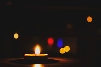 lighted tealight, bokeh photography, candle glow, warm light, dark background, bokeh effect, candle flame, foreground focus, soft lighting, ambient light, bokeh circles