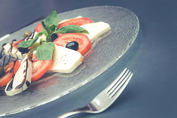 Caprese salad, tomatoes, mozzarella, fresh basil, olives, glass plate, italian cuisine, healthy eating, vegetarian, summer dish, meal presentation