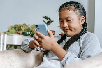 Asijská dívka, chytrý telefon, digitální zábava, pletené vlasy, gauč, mladá dívka, koncentrovaný, pomocí smartphonu, Vnitřní nastavení, neformální oblečení, Domácí prostředí
