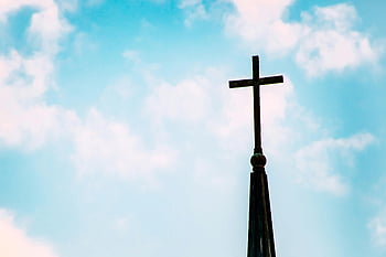 silhouette of cross, church spire, bright blue sky, clouds, religious symbol, cross silhouette, sky background, church architecture, spiritual imagery, faith symbol, cross against sky