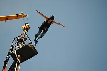 bungee jumping, thrill-seeker, leaps, platform, arms spread, freedom, adrenaline, outdoor adventure, extreme sports, sky, harness