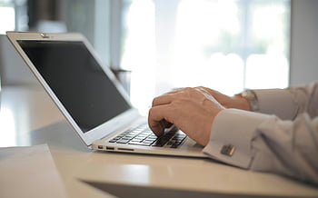 man using laptop, white table, hands typing, modern office, bright setting, close-up, laptop computer, work environment, professional setting, office desk, business person