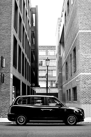 photo en niveaux de gris, voiture classique, ruelle urbaine, bâtiments en brique, photo monochrome, voiture garée, paysage urbain, noir et blanc, photographie d'architecture, scène de rue, véhicule d'époque