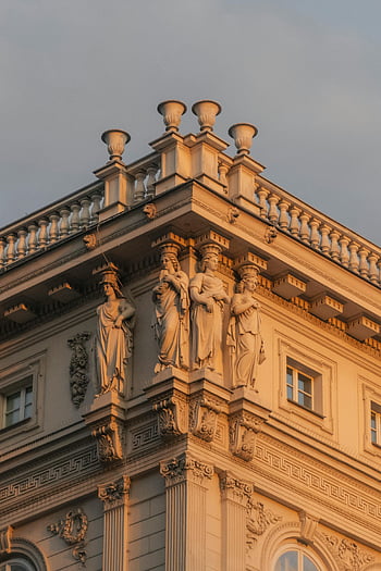 barokowy budynek, ozdobna fasada, rzeźby, zachód słońca, posągi, zbliżenie, top budynku, detale architektoniczne, architektura historyczna, elementy dekoracyjne, oświetlenie zachodzącego słońca