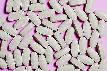 pilules de médicaments blancs, fond violet, comprimés ovales, concepts de soins de santé, concepts pharmaceutiques, vue rapprochée, pilules éparses, pilules blanches, surface violette, imagerie de soins de santé, imagerie pharmaceutique