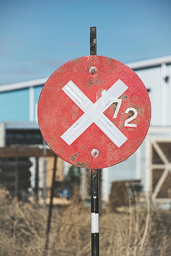 red circular sign, white X, industrial setting, outdoor sign, metal frame, red and gray, close-up photo, warning sign, no entry, prohibition sign, outdoor warning