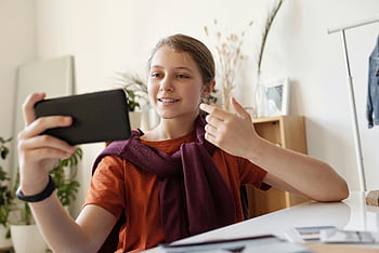 tinédzser lány, videohívás, okostelefon, kapcsolat, közlés, itthon, mosolygás, fekete smartphone, benti, alkalmi, technológia