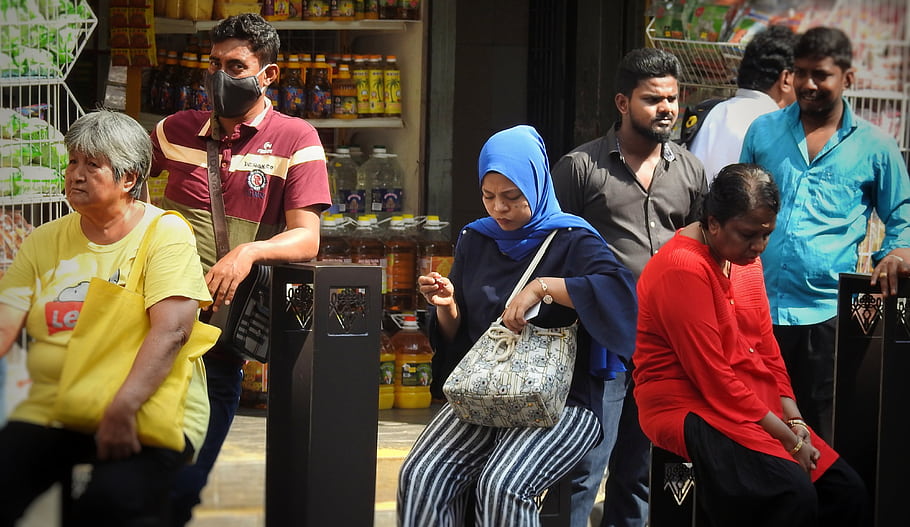 fermata dell'autobus, persone che aspettano, scena urbana, Gruppo eterogeneo, vita di strada, abbigliamento casual, buste della spesa, minimarket, giorno soleggiato, trasporto pubblico, vita di ogni giorno