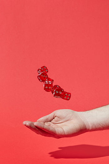 hand catching dice, red translucent dice, floating dice, vibrant red background, chance and uncertainty, red dice, hand under dice, dice in motion, red background, chance concept, uncertainty concept