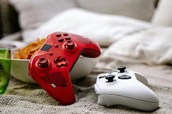 red Xbox controller, white Xbox controller, gaming controllers, cozy blanket, snacks, gaming themes, Xbox wireless controllers, red and white controllers, game controllers, gaming setup, cozy gaming setup