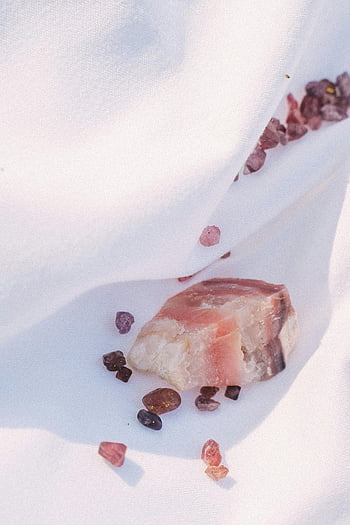 rose quartz, garnet gemstones, white textile, close-up, textured surface, pink gemstones, mineral stones, natural crystals, white background, gemstone photography, jewelry materials