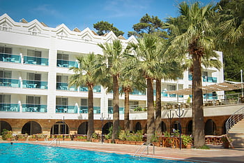 tropical resort, palm trees, swimming pool, modern architecture, white building, 3-storey building, surrounded with trees, stunning view, outdoor seating, resort amenities, vacation destination