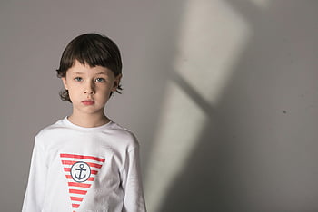Junge, Weißes langärmeliges Hemd, Nautisches Themenhemd, kleiner Junge, Innenfoto, sanfte Beleuchtung, Ankerdesign, gestreiftes Hemd, Kindermode, Freizeitkleidung, Innenporträt