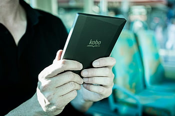 Kobo e-reader, public transportation, man reading, black Kobo tablet, e-book reader, travel reading, focused reading, digital reading, handheld device, commuter reading, e-reader device
