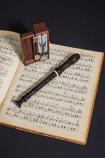 wooden flute, music sheet, vintage metronome, classic musical theme, brown wooden flute, book with notes, musical instruments, sheet music, vintage music, flute on book, metronome on music sheet