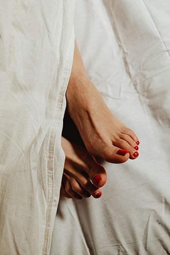 red pedicure, white sheets, close-up feet, relaxed morning, cozy vibe, red nail polish, white bedding, foot care, morning relaxation, cozy atmosphere, red toes