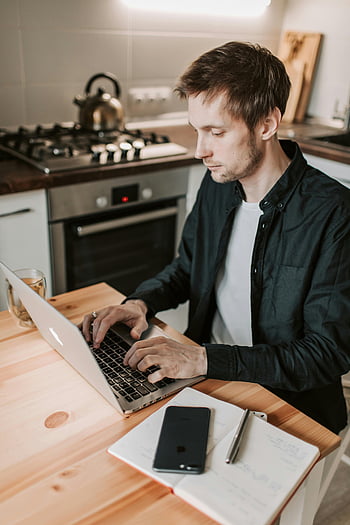 Mann mit Laptop, moderne Küche, Heimarbeit, junger Mann, Laptop, Kücheneinstellung, Lebensstil arbeiten, Fernarbeit, Innenministerium, von zu Hause aus arbeiten, digitaler Nomade